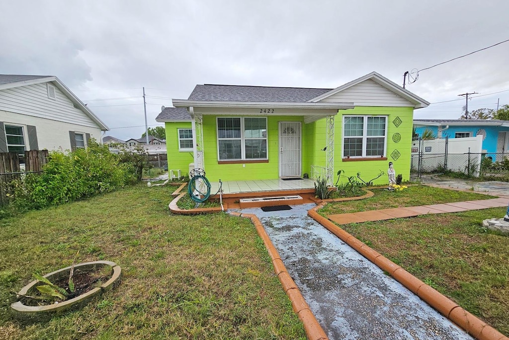 bungalow with a porch, fence, a front lawn, and roof with shingles