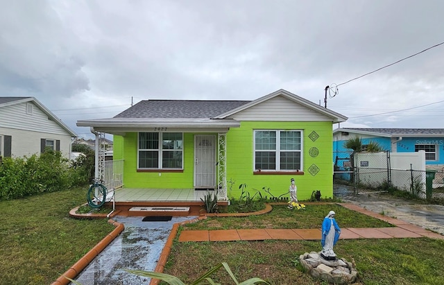 bungalow featuring a front lawn, fence, a porch, and roof with shingles