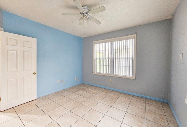 spare room featuring a textured ceiling, baseboards, a ceiling fan, and light tile patterned flooring