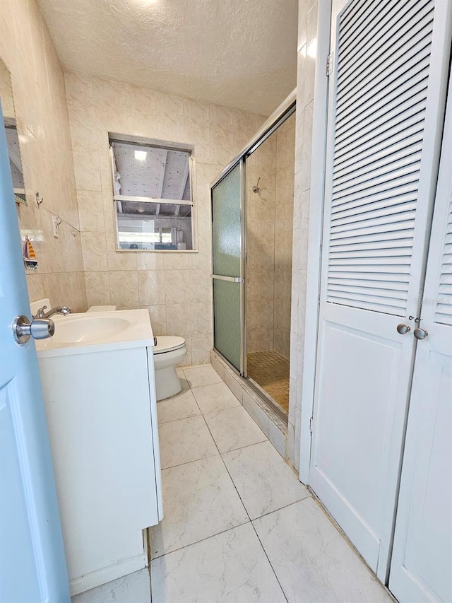 bathroom with a stall shower, toilet, a textured ceiling, and vanity