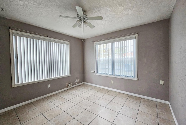 unfurnished room featuring a ceiling fan, a textured ceiling, baseboards, and light tile patterned floors