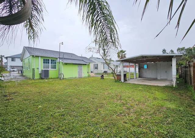 view of yard featuring fence, central AC unit, and a carport