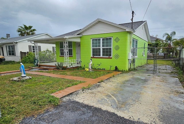 view of front of house featuring a gate, covered porch, fence, and a front lawn