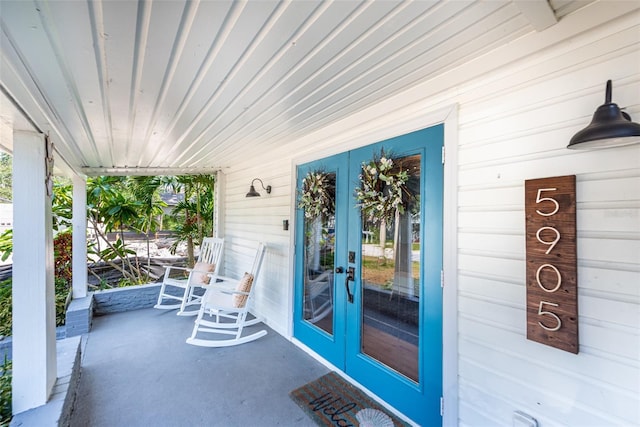 view of patio featuring a garage, a porch, and french doors