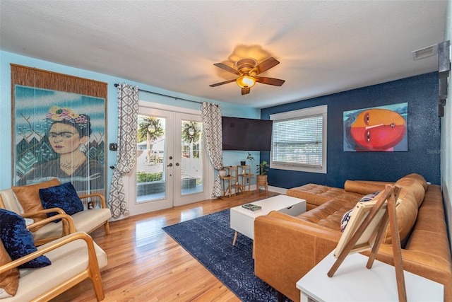 living area featuring a textured ceiling, ceiling fan, visible vents, light wood-style floors, and french doors