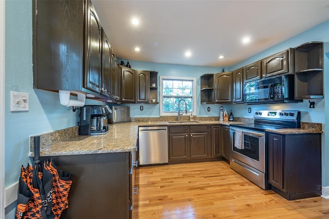 kitchen featuring stainless steel appliances, light wood-style floors, a sink, and open shelves