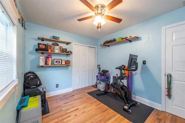 workout area featuring light wood-type flooring, ceiling fan, and baseboards