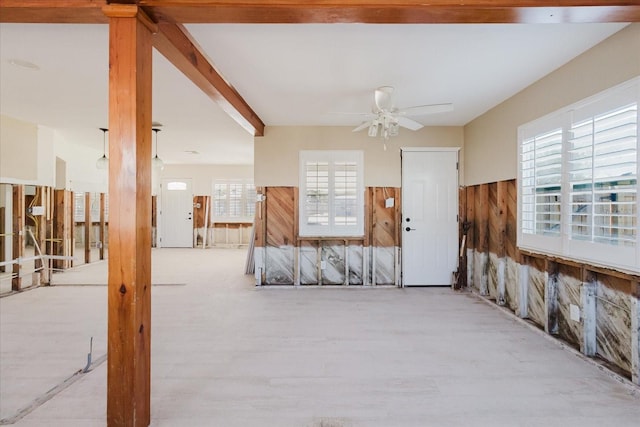 empty room with wooden walls, wainscoting, ceiling fan, and wood finished floors