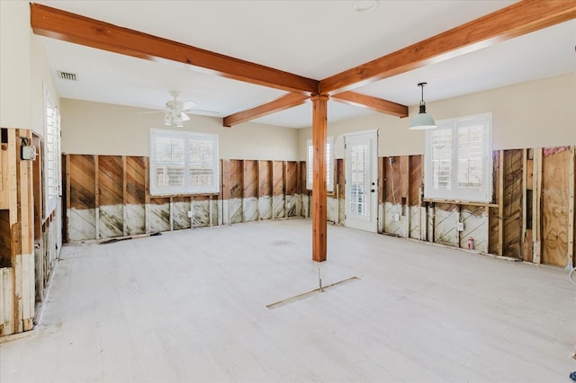 unfurnished room with beam ceiling, wooden walls, visible vents, and a wealth of natural light