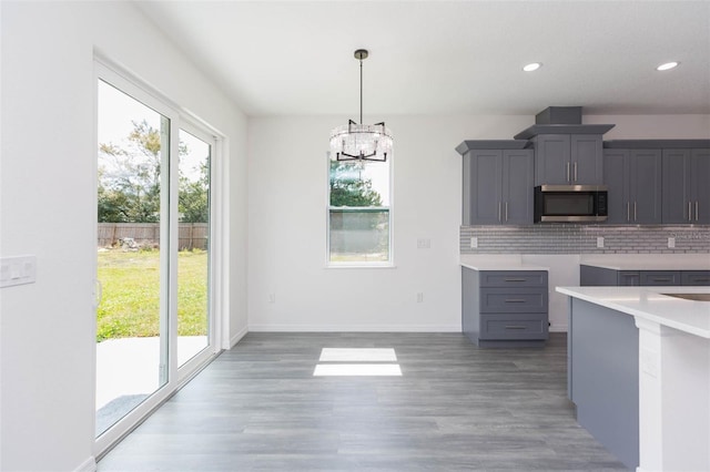 kitchen with tasteful backsplash, stainless steel microwave, gray cabinets, and a wealth of natural light