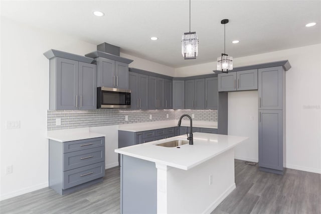 kitchen featuring gray cabinets, stainless steel microwave, a sink, and light wood-style floors