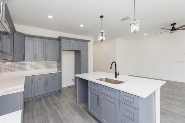 kitchen with decorative backsplash, visible vents, a sink, and gray cabinetry