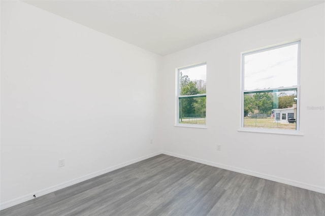 spare room featuring baseboards and wood finished floors