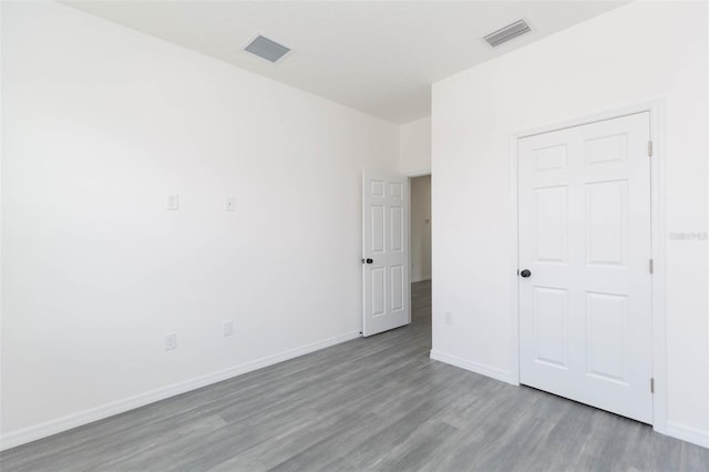 unfurnished bedroom featuring wood finished floors, visible vents, and baseboards