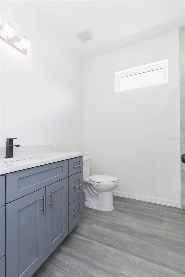 bathroom featuring wood finished floors, vanity, toilet, and baseboards