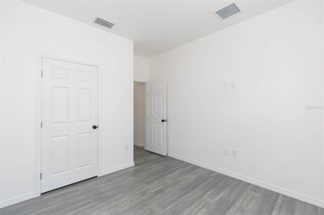 unfurnished bedroom featuring wood finished floors, visible vents, and baseboards