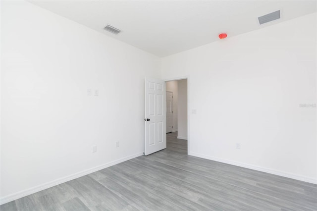 empty room featuring visible vents, baseboards, and wood finished floors