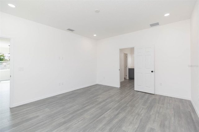 empty room featuring light wood finished floors, baseboards, visible vents, and recessed lighting