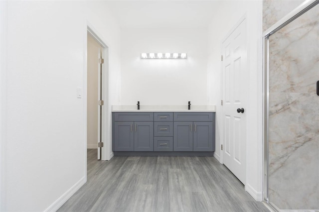 bathroom with a stall shower, a sink, and wood finished floors