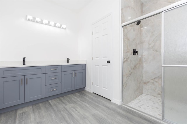 full bathroom featuring a sink, double vanity, wood finished floors, and a marble finish shower