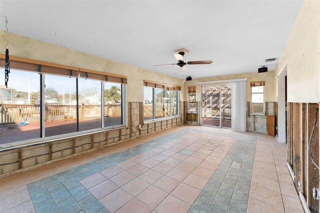 unfurnished sunroom with a ceiling fan, a healthy amount of sunlight, and visible vents