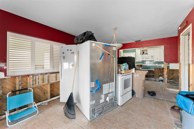 kitchen with white appliances, white cabinetry, backsplash, and light tile patterned floors