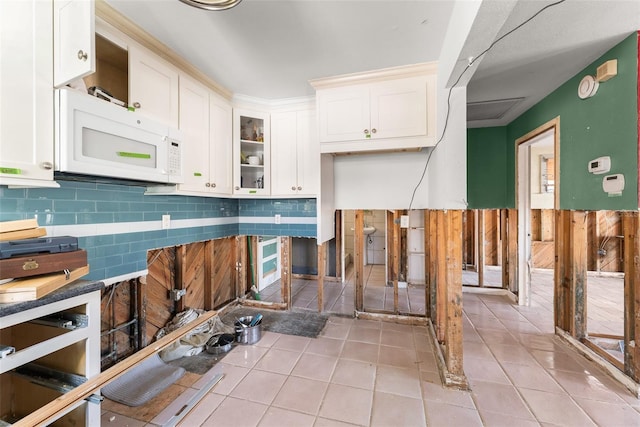 kitchen featuring white cabinetry, tasteful backsplash, light tile patterned floors, and white microwave