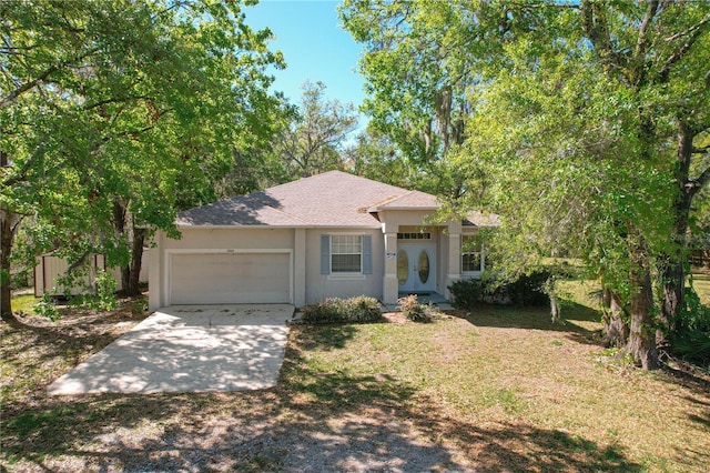 ranch-style home with an attached garage, driveway, a front yard, and stucco siding