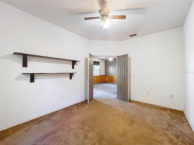 empty room with ceiling fan, carpet floors, visible vents, and baseboards