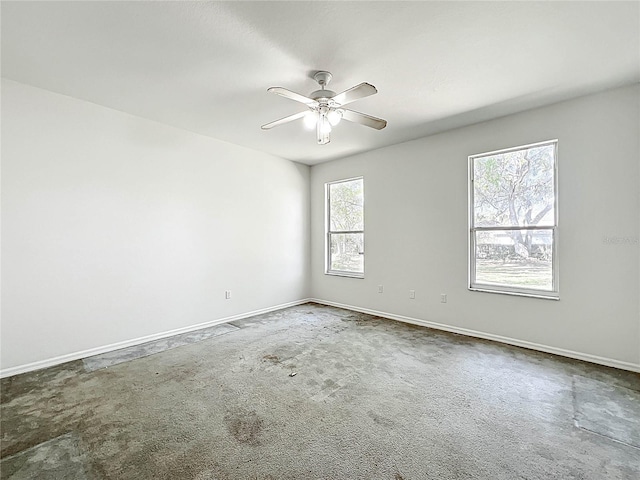 carpeted empty room featuring a ceiling fan and baseboards