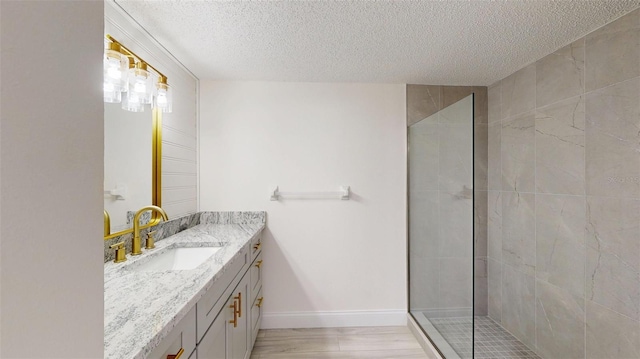 bathroom featuring baseboards, a textured ceiling, vanity, and walk in shower