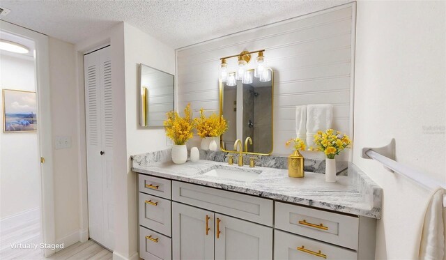 full bathroom with a textured ceiling, wood finished floors, vanity, visible vents, and a closet