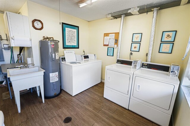 laundry area with electric water heater, dark wood finished floors, washer and dryer, a textured ceiling, and a sink