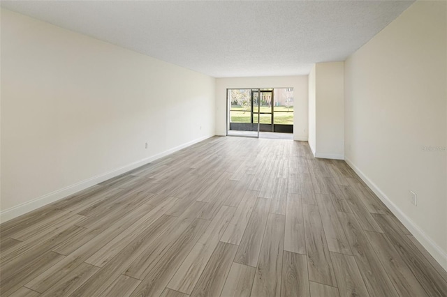 empty room with a textured ceiling, baseboards, and wood finished floors