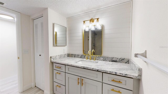 bathroom with vanity, wood finished floors, visible vents, a closet, and a textured ceiling