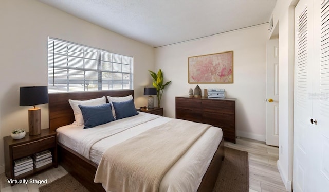 bedroom featuring baseboards, a closet, and light wood finished floors