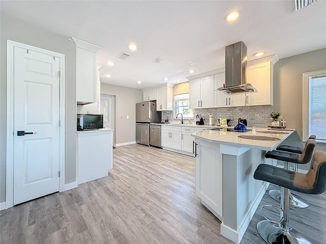 kitchen with visible vents, decorative backsplash, a peninsula, island exhaust hood, and stainless steel appliances