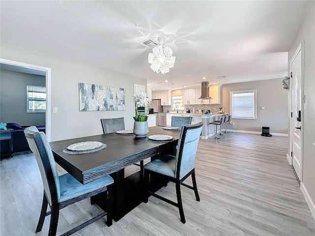 dining area featuring light wood-style floors, a textured ceiling, and baseboards