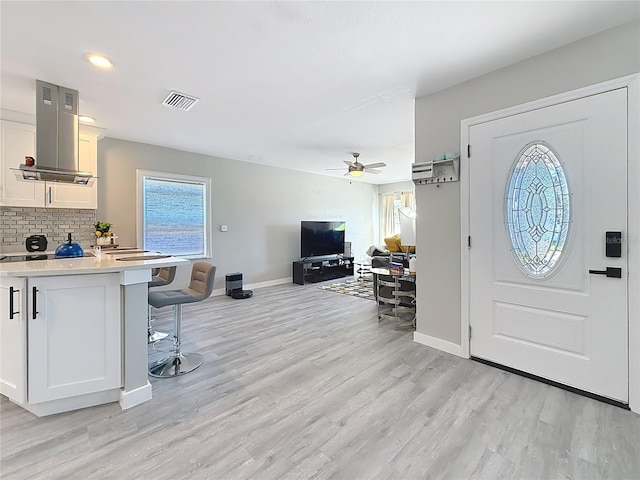 entrance foyer featuring light wood-style floors, baseboards, visible vents, and a ceiling fan