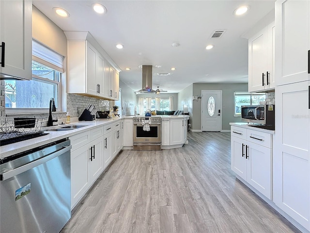 kitchen with stainless steel appliances, a peninsula, visible vents, tasteful backsplash, and island exhaust hood