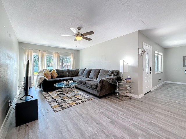 living room with plenty of natural light, a textured ceiling, baseboards, and wood finished floors