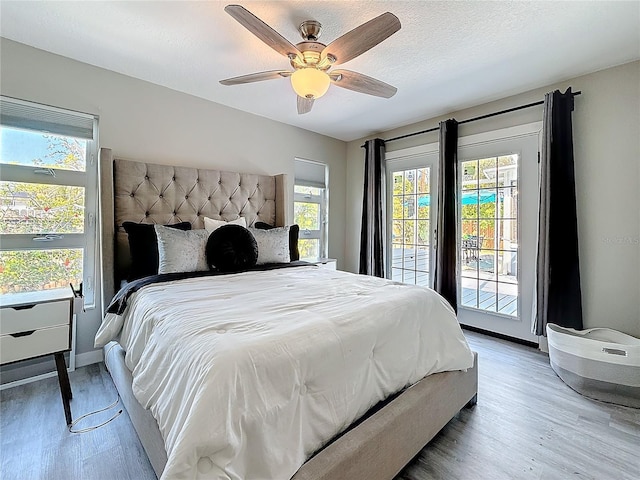 bedroom with access to exterior, a textured ceiling, baseboards, and wood finished floors