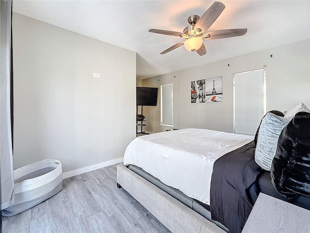 bedroom featuring baseboards, ceiling fan, a textured ceiling, and light wood finished floors