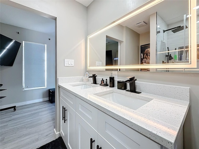 full bathroom with double vanity, baseboards, a sink, and wood finished floors