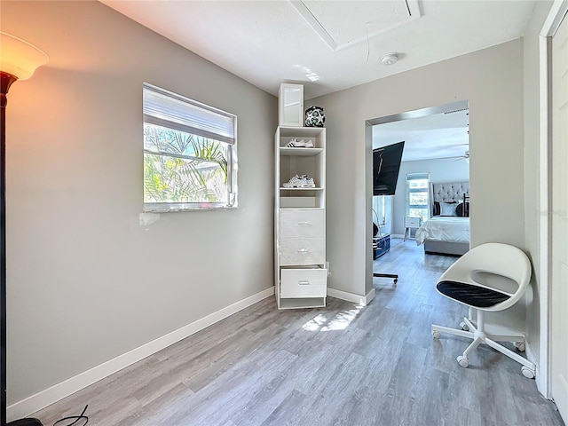 interior space featuring attic access, baseboards, and wood finished floors