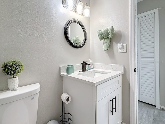 bathroom featuring toilet, wood finished floors, and vanity