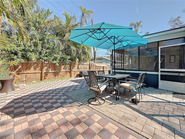 view of patio / terrace featuring a sunroom, fence, and outdoor dining space