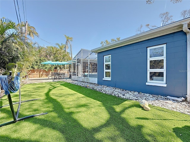 view of yard featuring a lanai, a patio area, and fence