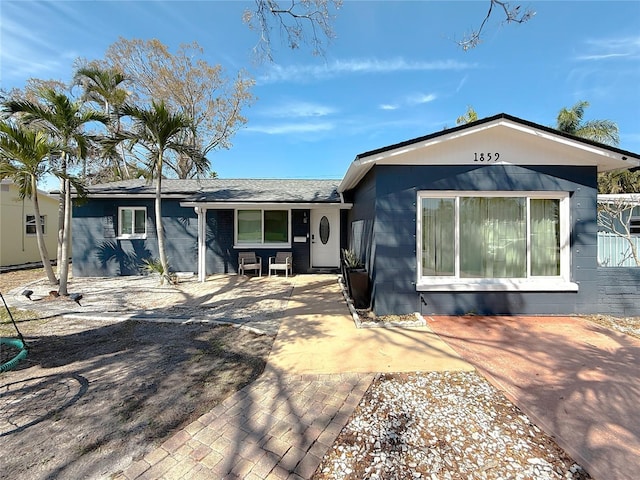 view of front of home with a patio and concrete block siding