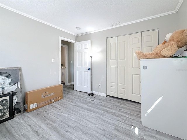 bedroom featuring a textured ceiling, wood finished floors, visible vents, and crown molding